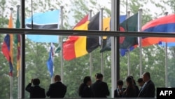 FILE - Workers stand near flags of countries participating in the Belt and Road Forum at one of the venues of the forum in Beijing, April 27, 2019. 