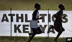 FILE - Junior athletes run past a sign for Athletics Kenya at the Discovery cross country races in Eldoret, western Kenya, Jan. 31, 2016.