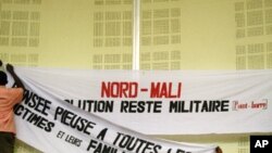 Workers at a meeting hall in Bamako, Mali, replace a banner that says 'The solution is military, period' for a forum, March 6, 2012.