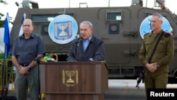 Israeli Prime Minister Benjamin Netanyahu (C) is flanked by Defense Minister Moshe Ya'alon (L) and Lieutenant-General Benny Gantz as he delivers a statement regarding an operation to locate three missing Israeli teenagers, at a military base near the West Bank Jewish settlement of Beit Haggai, near Hebron, June 19, 2014. 