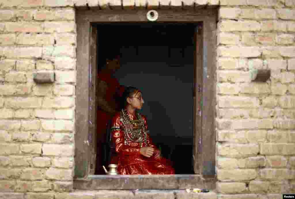 Living Goddess Kumari Samita Bajracharya is seen through a window of her house before she was taken to observe the Chariot Festival of Rato Machhindranath in Lalitpur, Nepal.