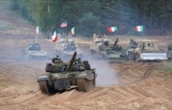 FILE - Military vehicles and tanks of Poland, Italy, Canada and United States are seen during NATO military exercises "Namejs 2021" at a training ground in Kadaga, Latvia, Sept. 13, 2021.