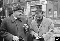 John Steinbeck tại chốt kiểm soát quân sự từ phía Tây Berlin, 11 tháng 12, 1963. Có một khoảnh khắc, Steinbeck chống lại một lính gác ở phía Đông và bước qua lằn sơn trắng phân cách biên giới Đông và Tây Đức. Ông thăm Berlin 5 ngày trong chuyến thăm Châu Âu 2 tháng, kết thúc bằng chuyến thăm Moscow. (AP Photo/Edwin Reichert)