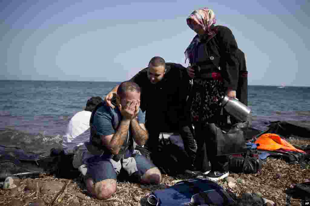 Yshar, left, a 36 year-old musician from Iran, reacts on the shores of the Greek island of Lesbos after crossing with others the Aegean Sea from Turkey on a inflatable dinghy.