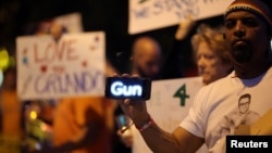 A man holds a scrolling message about guns on his smart phone at a candlelight vigil in West Hollywood, California, following the early morning attacks on a gay night club in Orlando, Florida, U.S. June 12, 2016. 