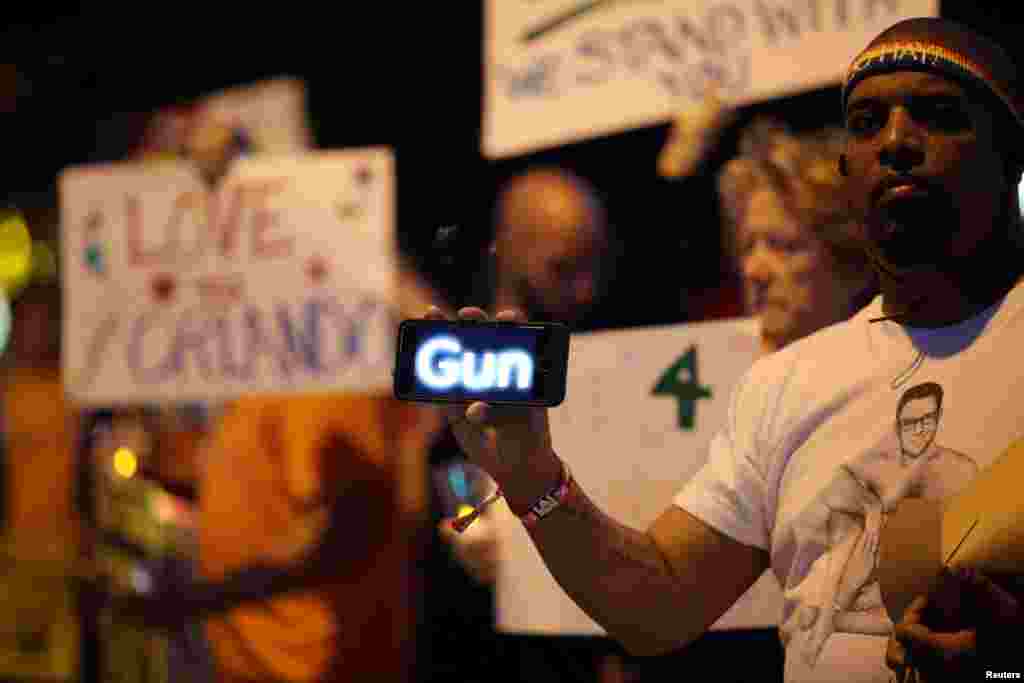 Um homem usa o seu telemóvel para passar uma mensagem sobre armas durante uma vig~ilai de velas em West Hollywood, California, na sequência do ataque à discoteca Pulse em Orlando, no Domingo de madrugada. Junho 12, 2016.