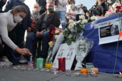 France -- A woman lights a candle on Republique Square during a demonstration Sunday Oct. 18, 2020 in Paris.