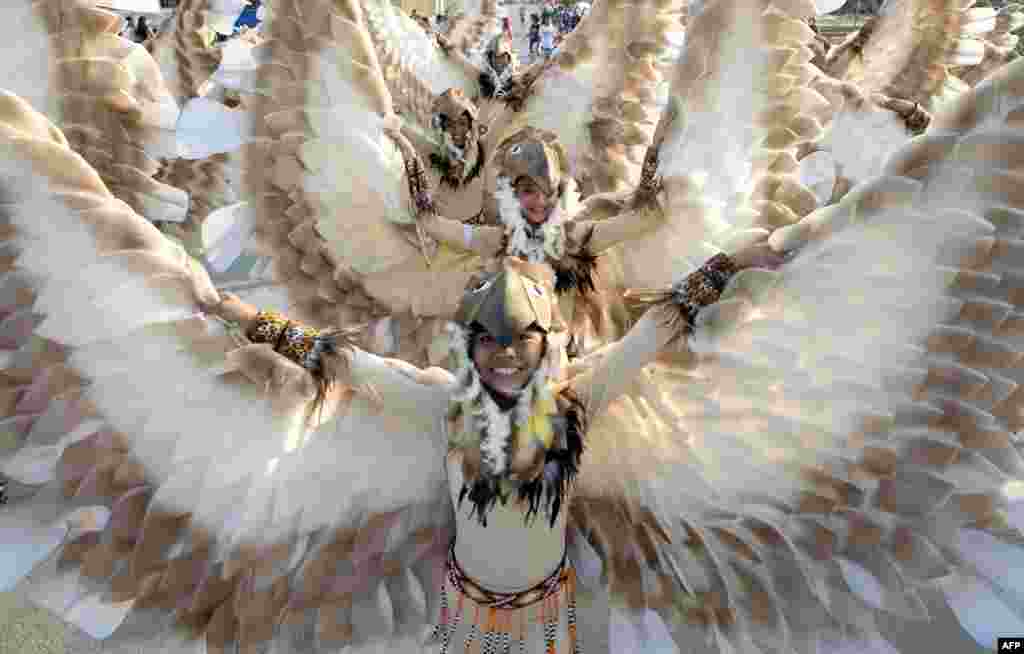 Para siswa mengenakan kostum burung menari dalam Festival Caracol tahunan di Manila, Filipina.