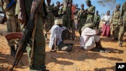 FILE - In this photo released by the African Union-United Nations Information Support Team, alleged al-Shabab members are blindfolded and guarded in Kismayo, southern Somalia on Oct. 3, 2012.