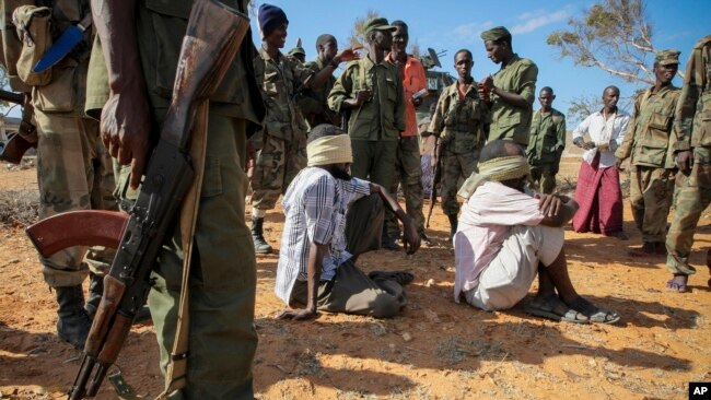 FILE - Alleged members of al-Shabab are blindfolded and guarded at a former police station by soldiers of the Somali National Army (SNA) in Kismayo, southern Somalia, Oct. 3, 2012.