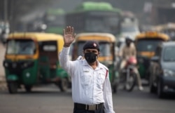 Seorang polisi lalu lintas mengenakan topeng untuk melindungi dirinya dari polusi udara di sebuah persimpangan jalan, saat berlangsungnya pembatasan kendaraan pribadi berdasarkan plat nomer mobil, di New Delhi, India, 4 November 2019.