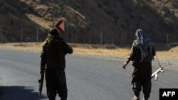 Seorang anggota Partai Pekerja Kurdistan (PKK) membawa senapan otomatis di jalan di Pegunungan Qandil, markas PKK di Irak utara, pada 22 Juni 2018. (Foto: AFP)