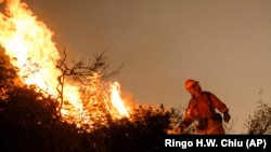 A firefighter uses special methods to fights the Holy Fire as it burns in the Cleveland National Forest along a hillside at Temescal Valley in Corona, California.