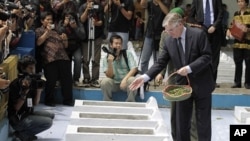 Dutch Ambassador to Indonesia Tjeerd de Zwaan, right, throws petals over graves at the Rawagede Hero Cemetery during commemoration in Rawagede, West Java, Indonesia, December 9, 2011.