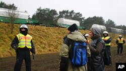 Police face demonstrators while in background the train with nuclear waste is heading for the storage in Gorleben, in Vastorf, northern Germany. German police cleared a sit-in of thousands of protesters attempting to block a shipment of nuclear waste and