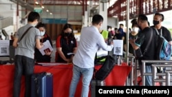 马来西亚和新加坡之间重新通航后，两国机场为注射过疫苗的旅客开通特别通道。图为旅客登上开往马拉西亚的大巴。