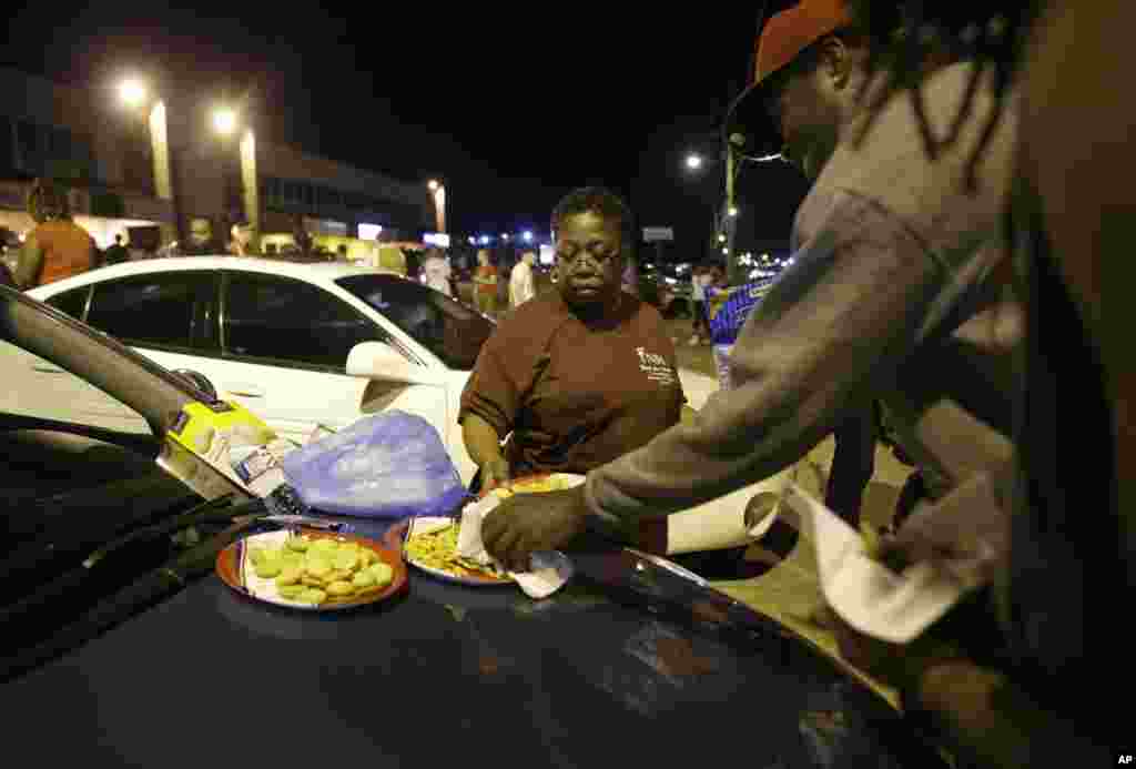 Cat Daniels provides snacks as a small group of protesters gather along West Florissant Avenue in Ferguson, Mo., Aug. 11, 2015.