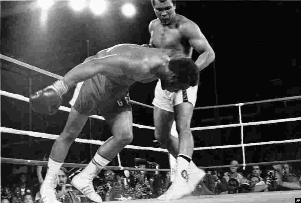 FILE - An Oct. 30, 1974 file photo shows Challenger Muhammad Ali watching as defending world champion George Foreman goes down to the canvas in the eighth round of their WBA/WBC championship match in Kinshasa, Zaire.