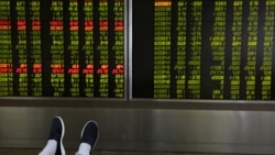 The feet of an investor are pictured as he looks at a board showing stock prices at a brokerage office in Beijing, China July 6, 2018.