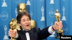 James Horner holds up two Oscars after winning for Best Original Song and Original Dramatic Score for his work on the movie "Titanic," at the 70th Annual Academy Awards, March 23, 1998.
