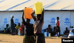 Women, who fled South Sudan, carry water in plastic containers on arrival at Bidi Bidi refugee’s resettlement camp in northern Uganda, Dec. 7, 2016.