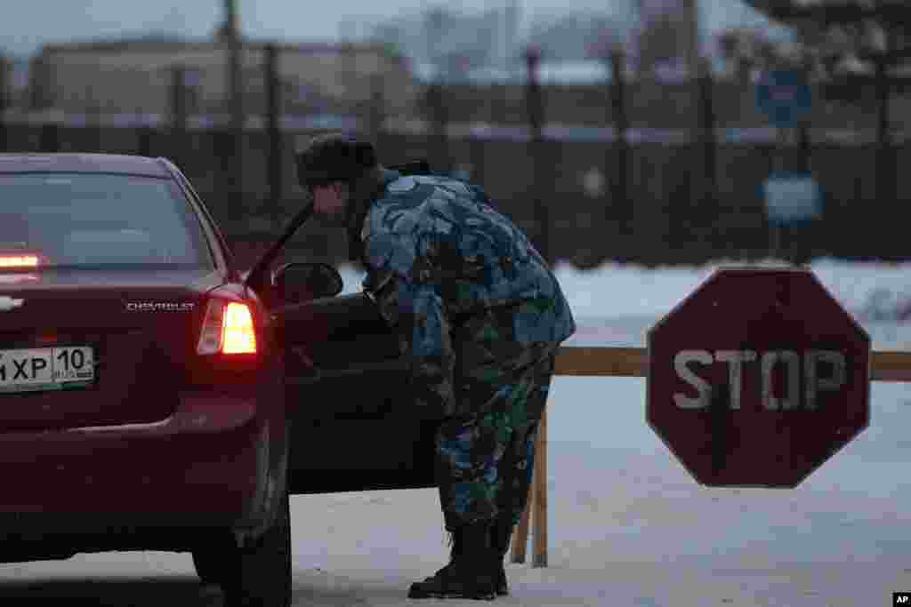 A prison service officer checks a car on the road at the prison where Mikhail Khodorkovsky was kept in Segezha, near Petrozavodsk, Russia, Dec. 20, 2013. 