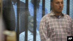 FILE - An Egyptian plain clothed policemen guards Egypt's ousted Islamist President Mohammed Morsi as he sits in a soundproof glass cage inside a makeshift courtroom at Egypt’s national police academy in Cairo, Egypt, April 21, 2015. 