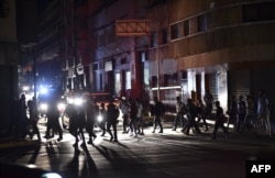 FILE - People cross a street during a power cut in Caracas, March 7, 2019.