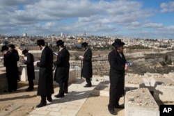 Jerusalem's Old City is seen while Jewish Orthodox men pray in a cemetery in Jerusalem, Dec. 7, 2017, a day after U.S. President Donald Trump's recognition of Jerusalem as Israel's capital.