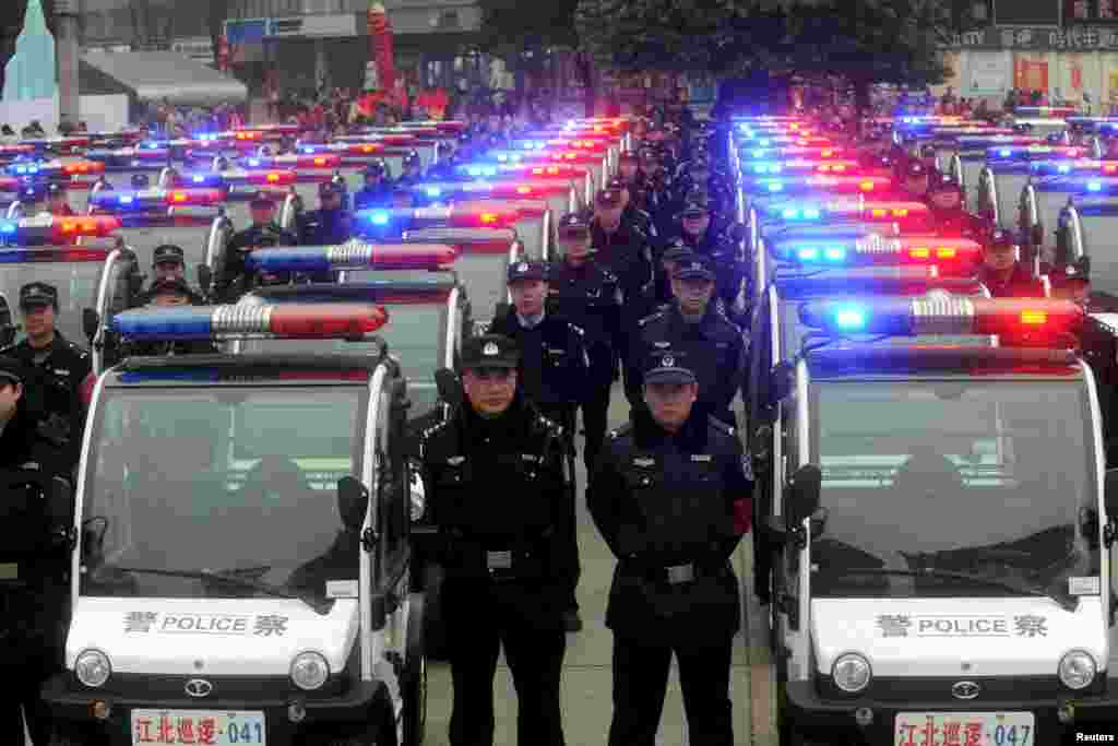 Orang-orang menonton polisi China yang memamerkan kendaraan patroli mereka yang baru di Kotamadya Chongqing, China.