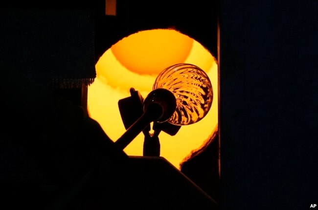 A glass-worker heats a glass artistic creation in a methane powered oven in Murano island, Venice, Italy, Oct. 7, 2021.