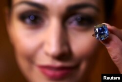 A model poses with a 12.03-carat cushion-shaped blue diamond mounted on a ring at Sotheby's auction house in Geneva, Nov. 4, 2015.