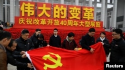 在北京舉行的中國改革開放40週年紀念展上人們展開一面中共黨旗。（2018年11月14日）