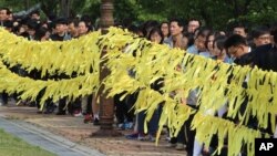 People wait to pay tribute to the victims of the sunken ferry Sewol as yellow ribbons with messages for missing passengers are displayed at a group memorial altar in Ansan, South Korea, May 4, 2014.