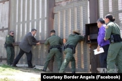 U.S. Customs and Border Patrol agents along with Rep. Juan Vargas open an emergency door at the U.S.-Mexico border in California during an event where immigrant families were able to spend three minutes together.