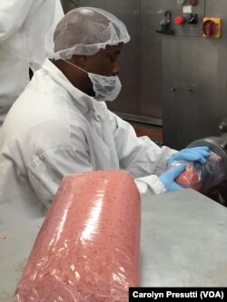 Gary Cannon fills a plastic sleeve with ground beef as it comes out of the cylinder.