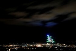 Pohon Natal terbesar di dunia menyala di lereng Gunung Ingino di kota abad pertengahan Gubbio, Italia, 7 Desember 2020. (Foto: REUTERS/Yara Nardi)