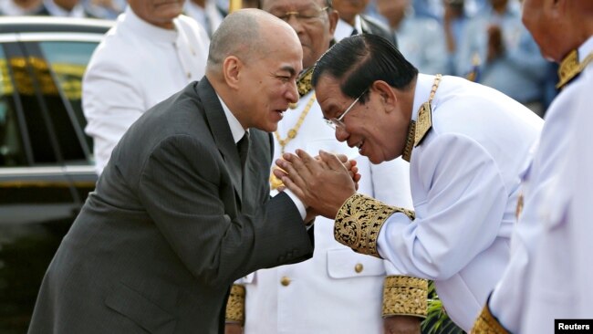 FILE - Cambodia's King Norodom Sihamoni is greeted by prime minister Hun Sen during the celebration marking the 64th anniversary of the country's independence from France, in Phnom Penh, Cambodia, Nov. 9, 2017.