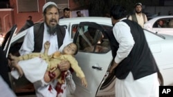 A man carries a wounded boy in a hospital, after a car bombing outside a sports stadium in Lashkargah, capital city of southern Helmand province, Afghanistan, March 23, 2018.