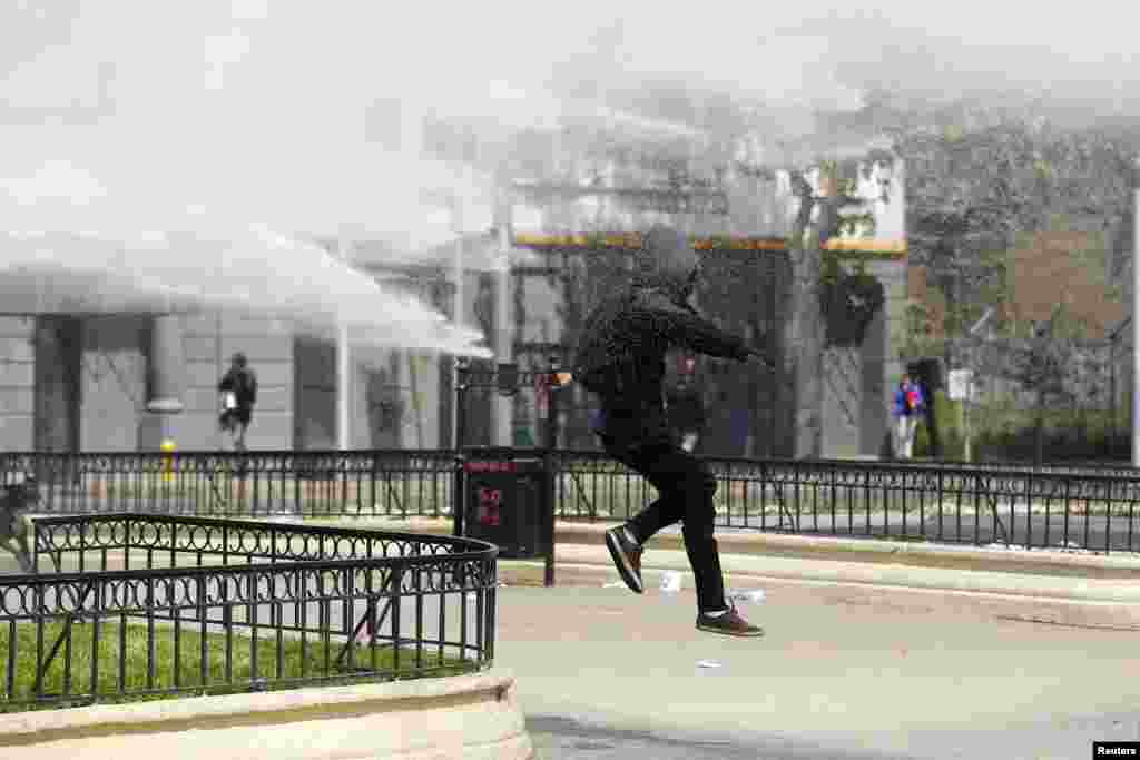 A student protester runs from a jet of water released from a riot police vehicle during a demonstration against the government to demand changes and an end to profiteering in the education system in Santiago, Chile.