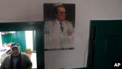 In this photo taken on Thursday, Jan. 23, 2020, Uros Trainovic walks inside his house decorated with picture of former Yugoslav communist president Josip Broz Tito, in the village of Blagojev Kamen, Serbia. (AP Photo/Darko Vojinovic)