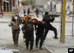 Các lực lượng an ninh Iraq và chiến binh bộ tộc Sunni sơ tán một phụ nữ bị Nhà nước Hồi giáo bắn bị thương.