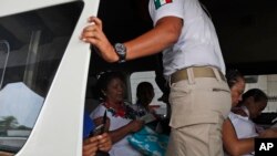 FILE - An immigration agent checks the identity card of a woman at a temporary checkpoint in the outskirts of Tapachula, Chiapas state, Mexico, April 29, 2019.