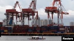 FILE - A small boat moves past one of the country's busiest ports at a portion of Manila Bay.