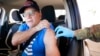 消防员杰弗里·狄龙（Jeffrey Dillon）坐在车里拉起衬衫袖子，在德克萨斯州达拉斯县卫生局设立的疫苗现场接种辉瑞疫苗加强剂。（2021年11月30日美联社照片）
