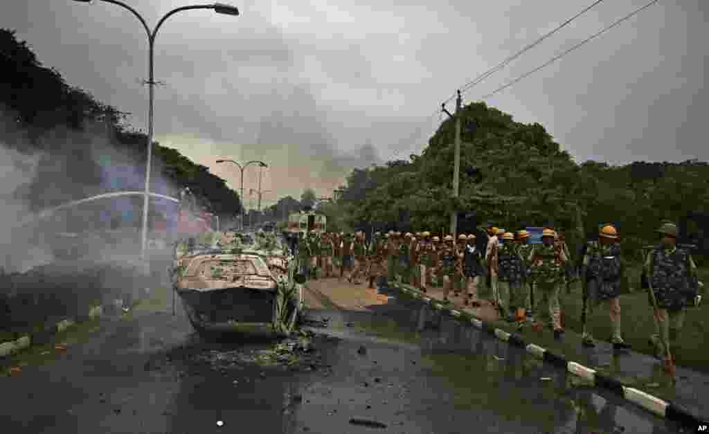 Policemen patrol past a vehicle vandalized by Dera Sacha Sauda sect members near in Panchkula, India.