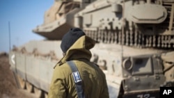 An Israeli soldier stand by a tank near the border with Syria in the Israeli-controlled Golan Heights, Monday, Nov. 28, 2016.