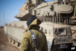 FILE - An Israeli soldier stands by a tank near the border with Syria in the Israeli-controlled Golan Heights, Nov. 28, 2016. Last month the BBC broadcast satellite images showing new buildings being erected 50 kilometers from Israeli installations on the Golan Heights. Iran is suspected of being behind the construction.