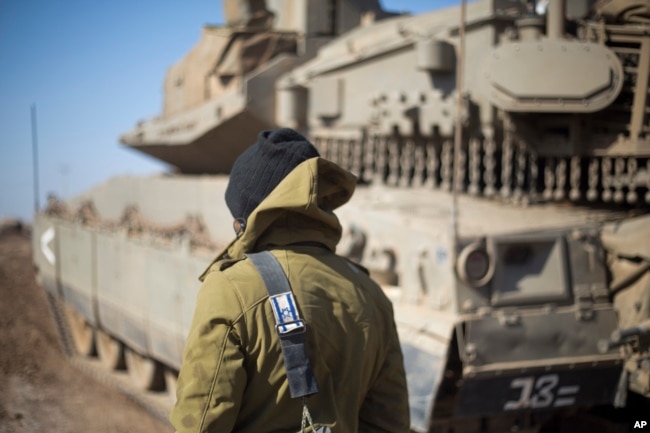 FILE - An Israeli soldier stands by a tank near the border with Syria in the Israeli-controlled Golan Heights, Nov. 28, 2016. Last month the BBC broadcast satellite images showing new buildings being erected 50 kilometers from Israeli installations on the Golan Heights. Iran is suspected of being behind the construction.
