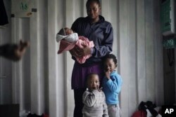 In this Sept. 23, 2019 photo, Prudence Aimee, 30, from Cameroon poses for a photo with her children, from left Ange, Wifrid, 1, and William, 3, aboard the humanitarian rescue ship Ocean Viking in Italian waters off the Sicilian town of Messina, southern Italy, hours before disembarking. Aimee left Cameroon in 2015, and when her family heard nothing from her for two years, they thought she was dead. But she was in detention and incommunicado. In nine months at Libya's Abu Salim detention center, she saw “European Union milk” and diapers delivered by UN staff pilfered before they could reach migrant children, including her toddler son. Aimee herself would spend two days at a time without food or drink. (AP Photo/Renata Brito)